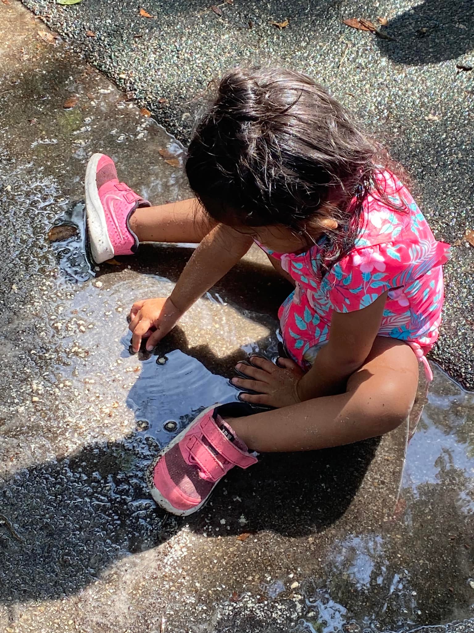 toddler sitting and playing in a puddle